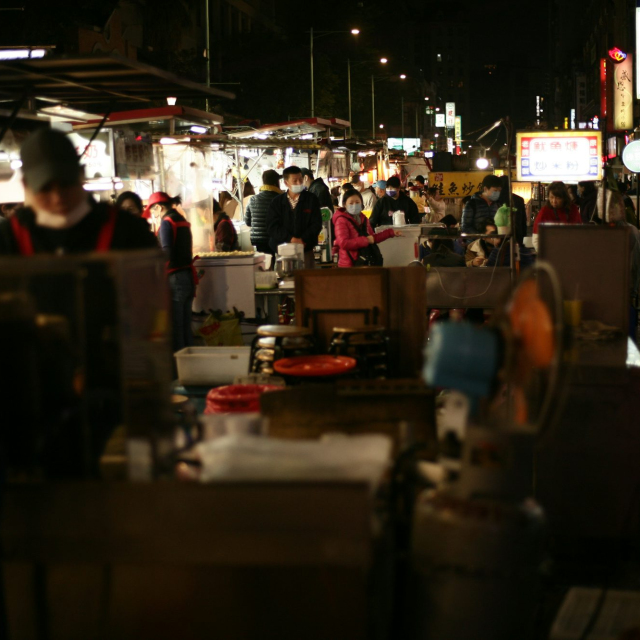 A group of people walking around a market at night