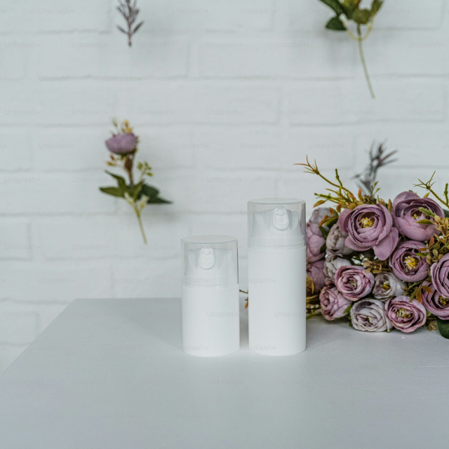 A white table topped with two bottles of lotion next to a bouquet of flowers