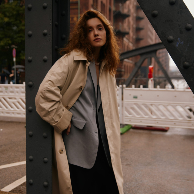 A woman leaning against a metal structure in a city