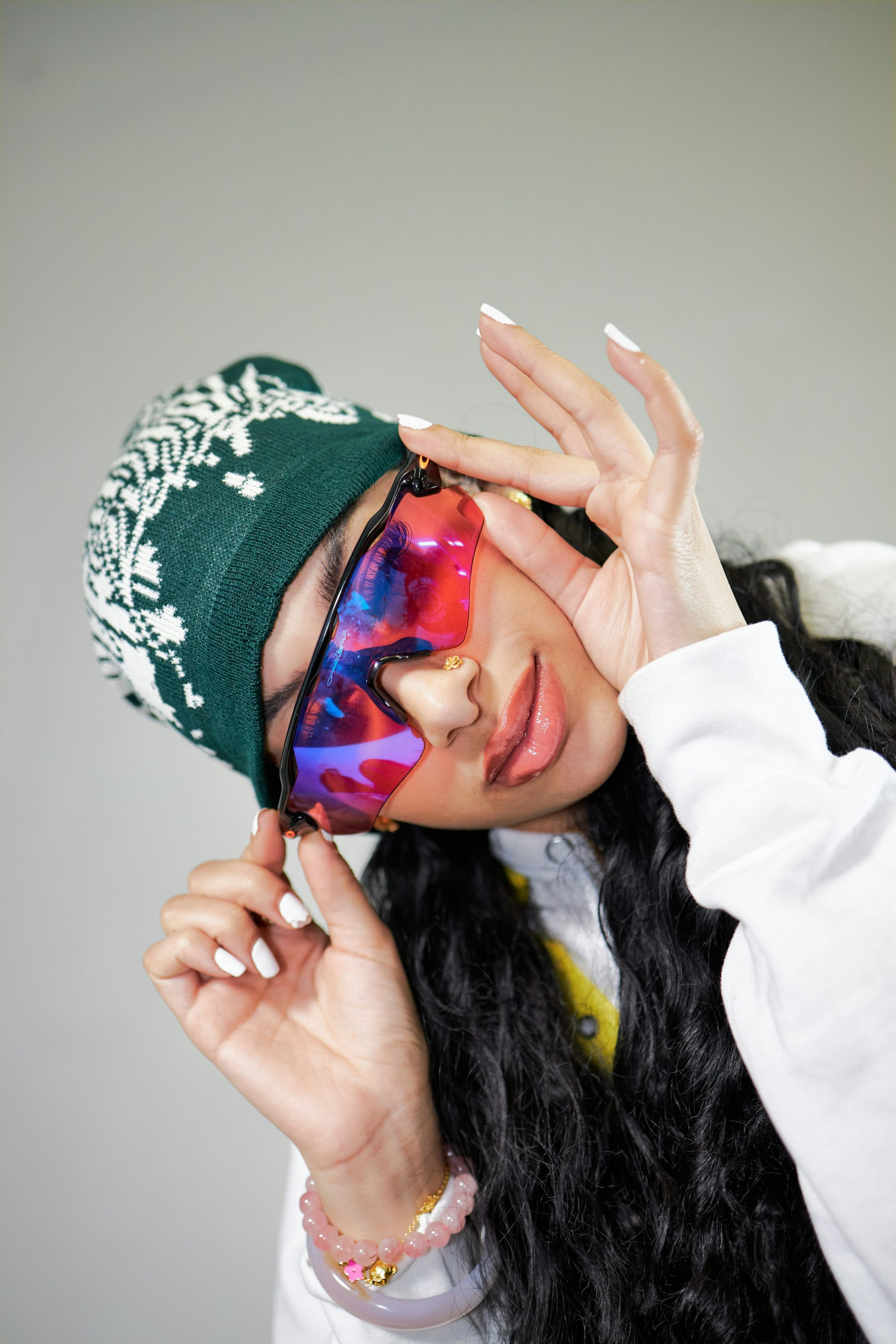 A woman wearing a green hat and a tie dye mask