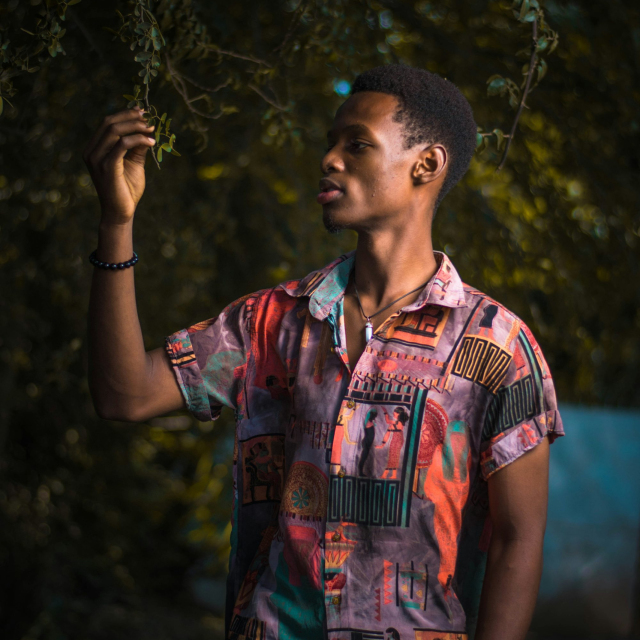 Man in blue and red button up shirt standing and holding his face