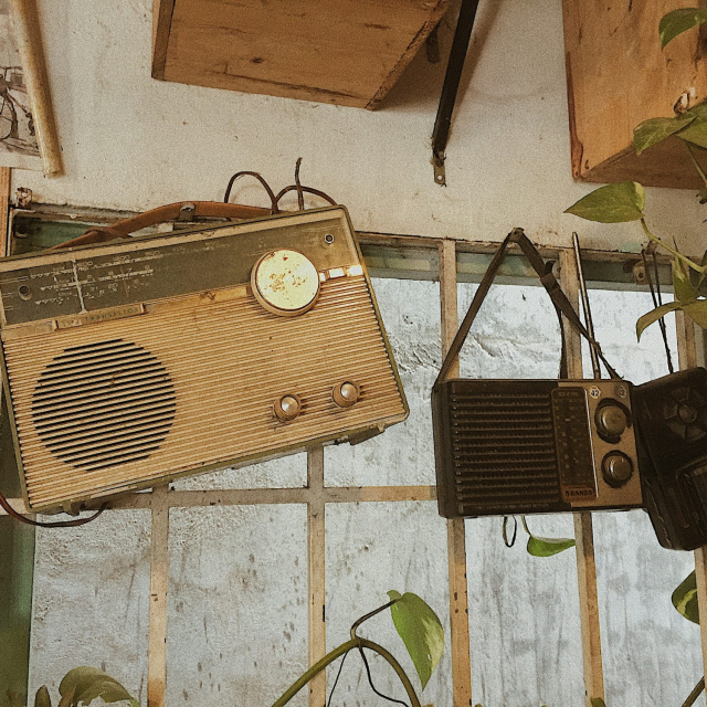 Three assorted-color radios hang on wall